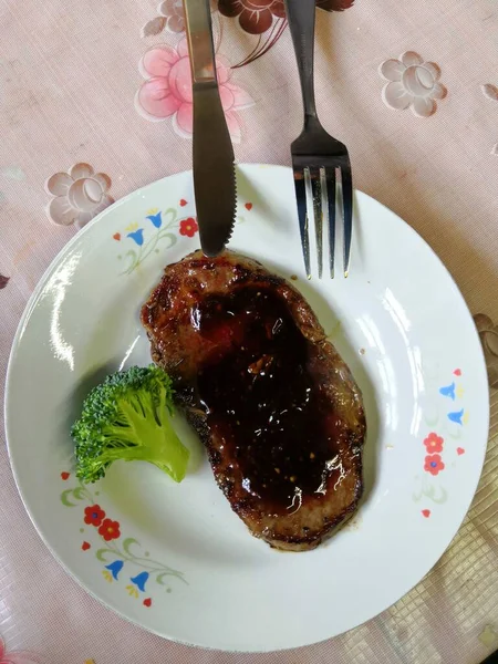 grilled pork steak with sauce and fork on white plate