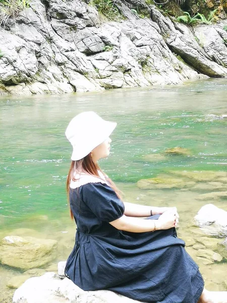 young woman sitting on the edge of the river