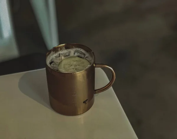 a cup of coffee with a green tea on a wooden table