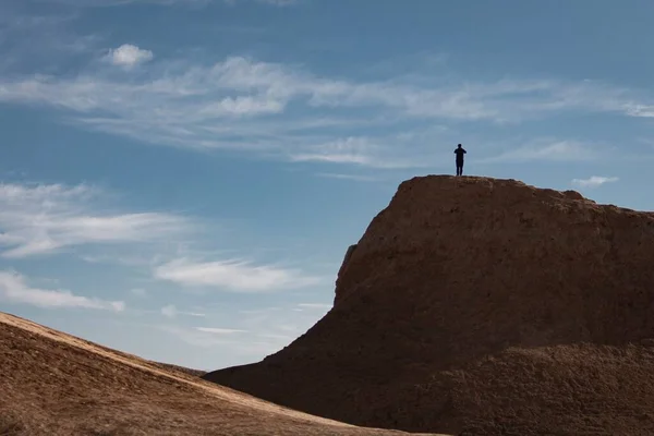man in a desert with a backpack on the top of the mountain