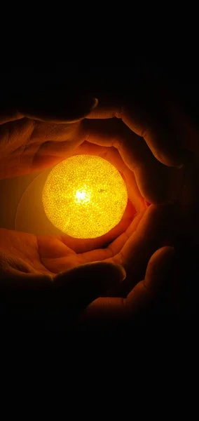 female hand holding a burning moon in the night sky