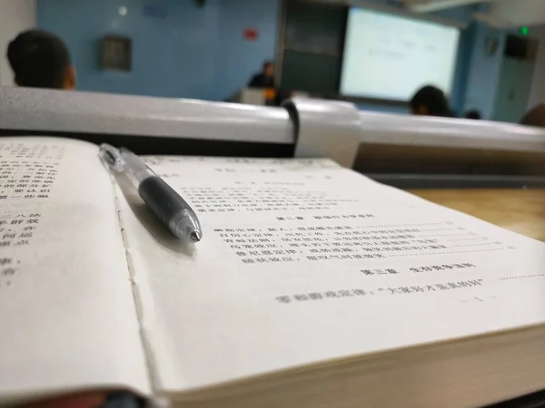 close up of a book with a pen and a pencil