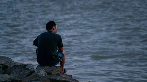 man sitting on the pier on the sea coast