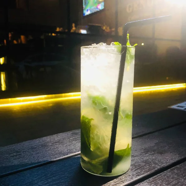 a glass of cocktail with ice and lemon on a bar counter