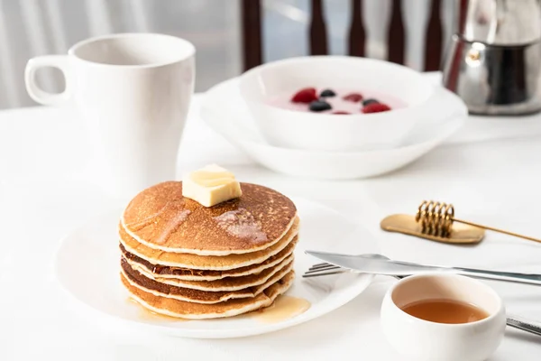 stack of pancakes with honey and berries on white background