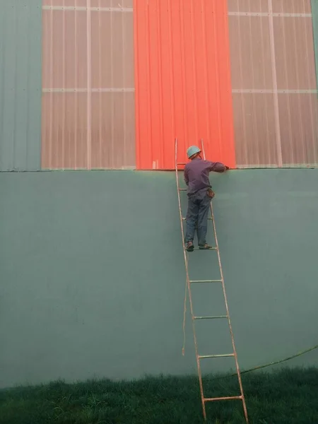 man with a ladder on the roof of the building