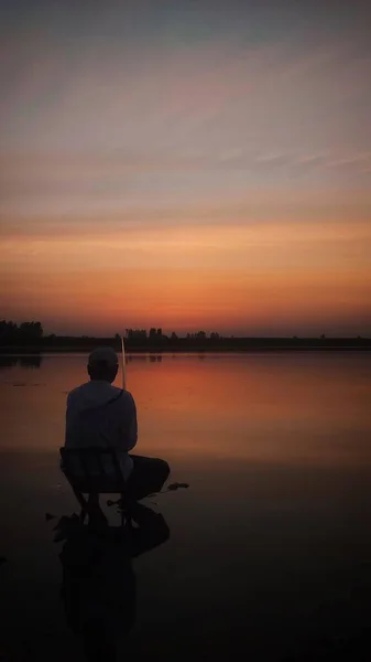 silhouette of a man sitting on the lake