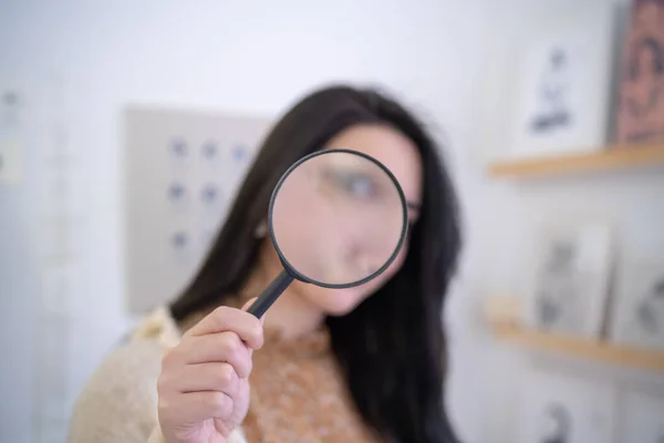 woman looking through magnifying glass, close up