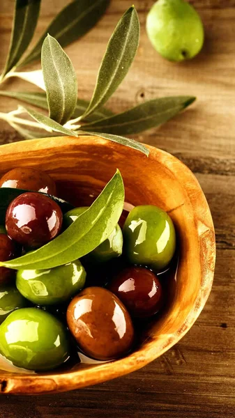 green olives and olive oil on wooden background