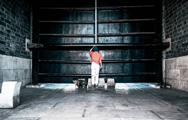 a man in a black jacket and a red hat and a white shirt on a concrete wall