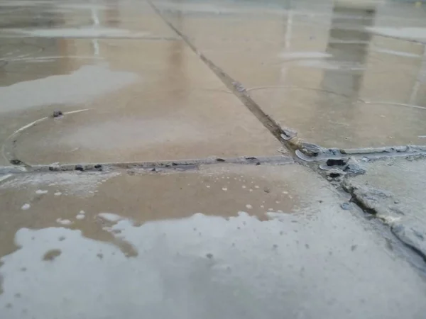 dirty concrete floor with a puddle of water