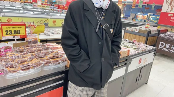man in a white coat with a tray of bread and a bag of wine in the supermarket