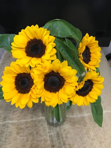 beautiful bouquet of sunflowers in a vase on a wooden background