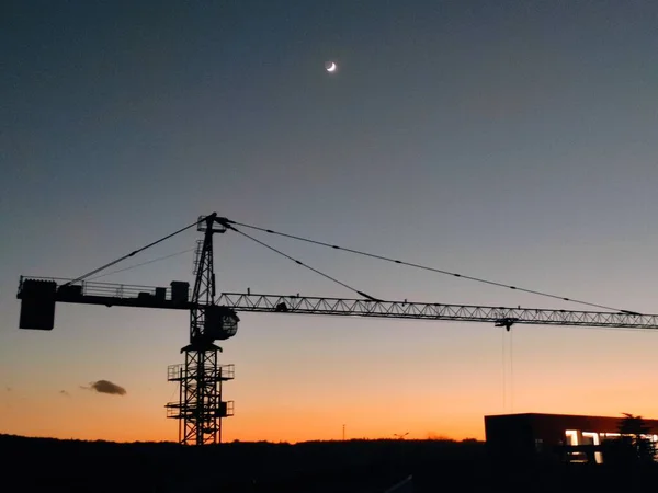 silhouette of a construction crane on the background of the building