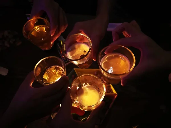 woman pouring cocktail in a glass with a candle in the background