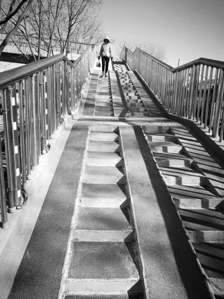 black and white photo of a man and woman walking on the bridge