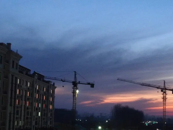 silhouette of a building with a crane and a house