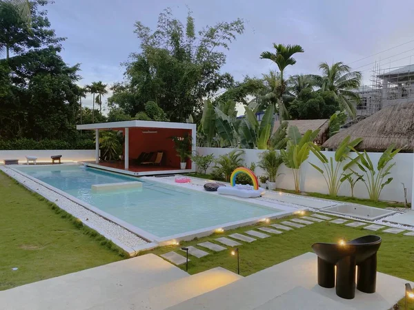 swimming pool with green grass and palm trees
