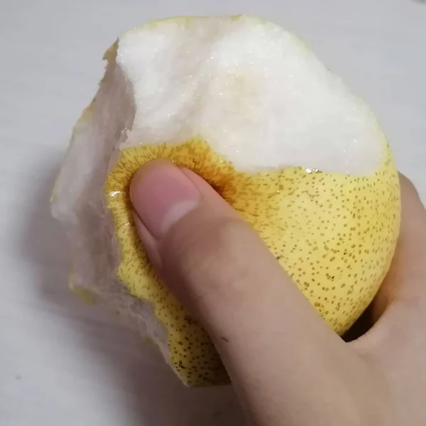 hand holding a white sponge with a glass of water