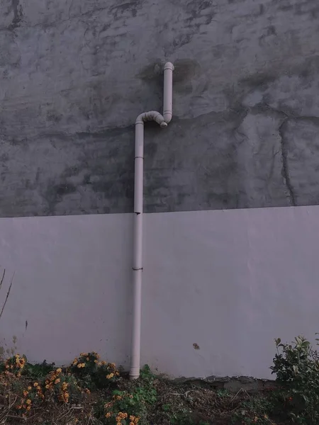 old concrete wall with a metal pipe and a black hole