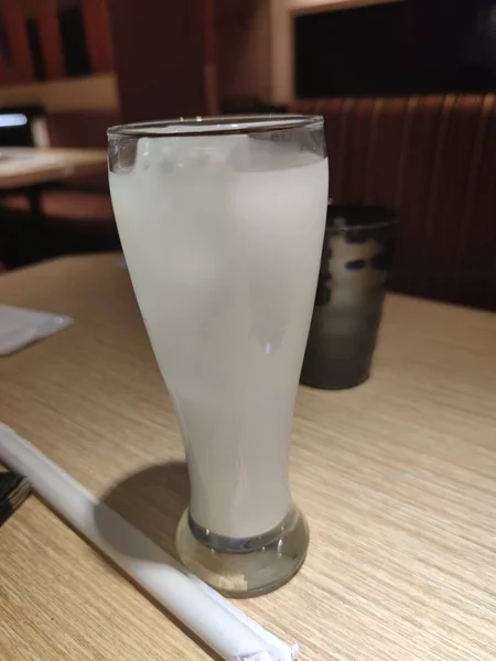 glass of milk and ice cubes on wooden table