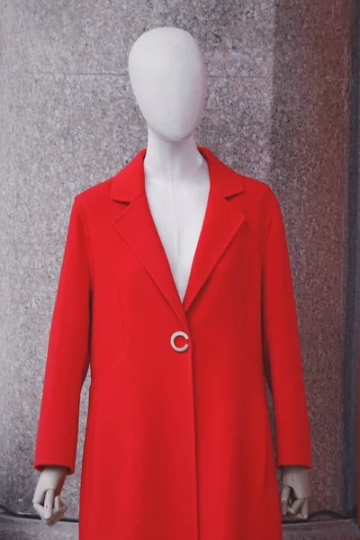 mannequin in a red jacket and a white blouse on a gray background