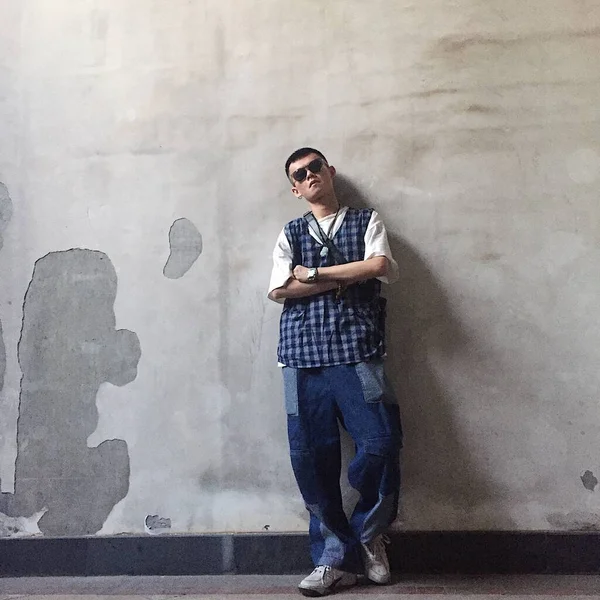 young man in sunglasses standing near the wall and looking away