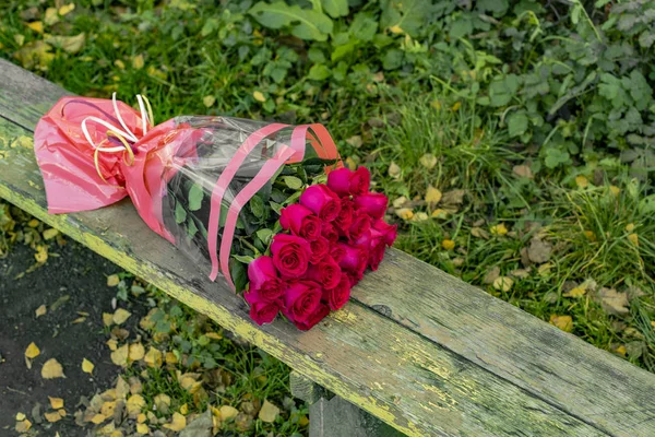 sad picture of broken relationship abandoned rose bouquet on poor wooden bench outdoor space environment background, copy space