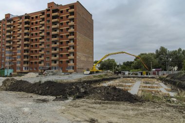 Bulutlu hava ve gri gökyüzünde vinç endüstriyel ağır ekipmanlarla inşaat süreci 