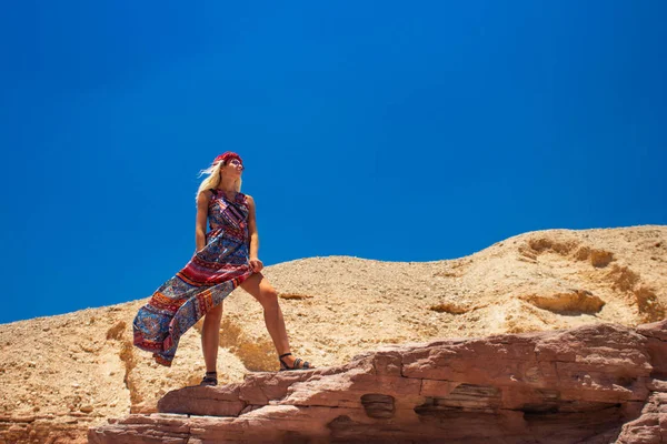 風になびく長いドレスで壮大なセクシーな女性ポーズファッション写真砂漠の岩あなたのテキストのための空の青空背景コピースペースと風景環境乾燥 — ストック写真