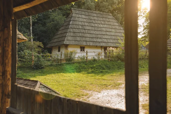 ウクライナの村の伝統的な農村部の田舎の側の朝の日の出のグレアライトと木製のフレームポーチからわら屋根と粘土ハウスの景色 — ストック写真