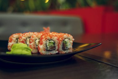 Hafif odaklı suşi, Alacakaranlık Restoranı 'nın iç yemek fotoğrafçılığı konseptinde siyah tabakta yuvarlanıyor. 