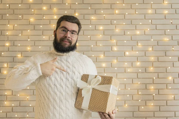 圣诞大减价寒假市场概念彩色照片带礼品盒的胡子男子肖像画在喜庆的白色室内环境砖墙黄色车库照明背景下 复制空间 — 图库照片