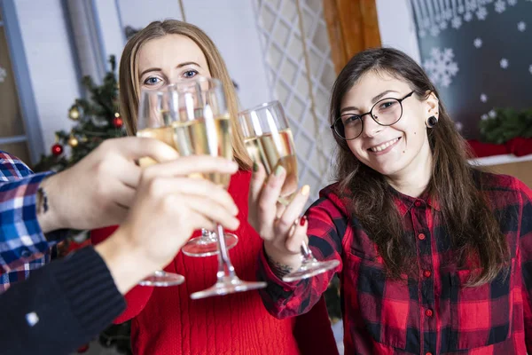 Christmas eve corporate party scene with adorable photogenic young adult smiling female portrait center of composition in company with glasses of champagne