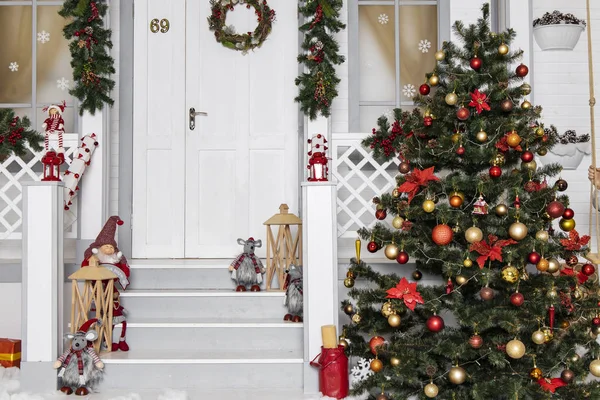 Şenlikli bir Noel arkaplanı beyaz çevre dekore edilmiş ağaç ve ahşap evin sundurması oyuncaklarla süslenmiş 