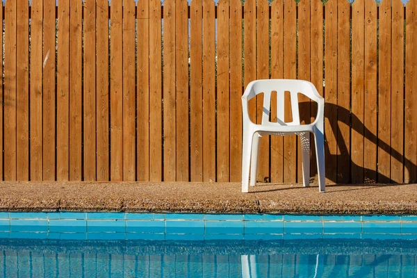 simple background exterior design back yard swimming pool space with white plastic chair and wooden deck wall background with empty copy space for your text here