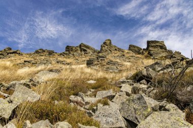 Kayalık dağlar tepenin altından öngörüyle tepeden manzaralı tepede keskin taşlar üstte ve canlı mavi gökyüzü beyaz bulutlar duvar kağıdı arka planda boş kopya alanı 