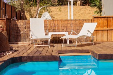 Güneş yatağı arka bahçe uzay mobilyaları yaz tatilinde yüzme havuzunun yanındaki villa dinlenme yeri. 