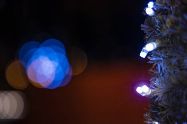 Bayramlarda hafif odaklı çelenk lambaları parlaklığı ve bulanık gece arkaplanındaki ışık ışınlarını aydınlatır. Bokeh ile birlikte. Metinleriniz için boş kopya alanı 