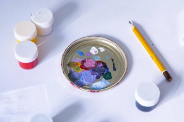 Çocukların hobisi. Beyaz kağıt arkaplanda kurşun kalemle karışık boya paleti. Boşluğu kopyala.  