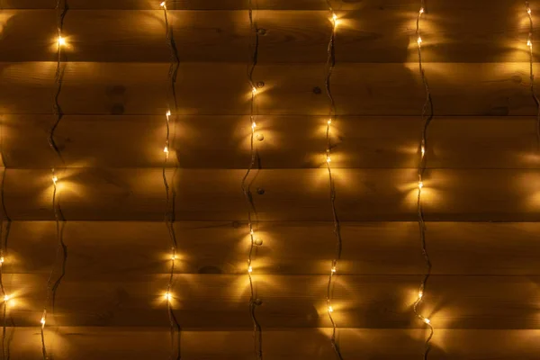 Ambiance chaleureuse et confortable à la maison dans la chambre en bois fond de mur de terrasse avec guirlande lumière jaune illumination vacances d'hiver temps de la veille de Noël — Photo