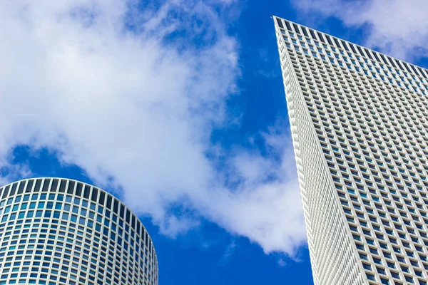 Ciudad moderna rascacielos torre edificios fachada exterior escorzo desde abajo en vivo azul cielo blanco nubes esponjosas fondo de claro tiempo día — Foto de Stock