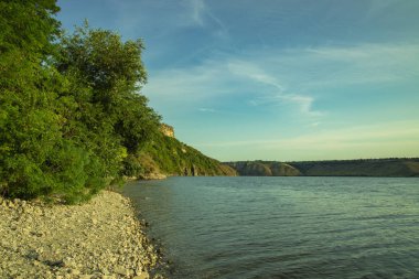 Sakin göl sularının Avrupa ilkbahar manzarası yeşil yapraklar ve taş kıyısı, uzayın kopyası.