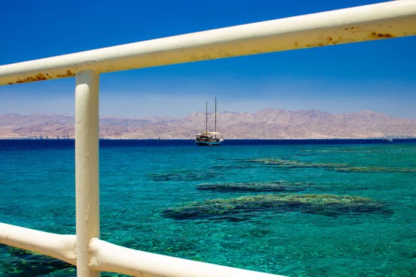 Summer time cruise vacation trip touristic agency pattern concept of liner on Red sea waters in Gulf of Aqaba Middle East district, white fence frame work foreground — Stock Photo, Image