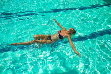 woman floating on a back in swimming pool resort hotel summer time vacation season clipart