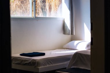 empty rustic room of cheap hotel apartments with bed white sheet and morning sun light ray through window