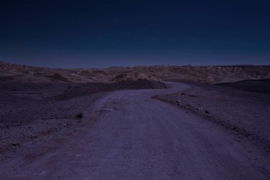 Uzun pozlu çöl manzarası yıldızlı mavi gökyüzü fotoğrafçılığı çorak arazinin kır yolu ufuk çizgisindeki dağlara gider.