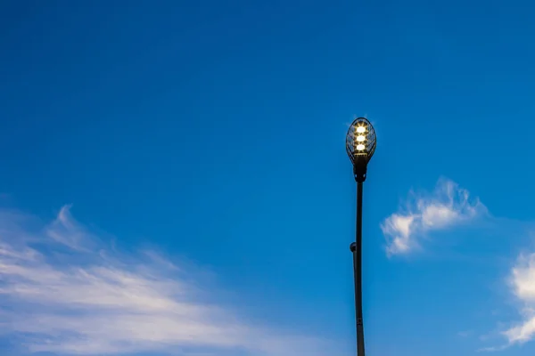 Illuminazione della lanterna stradale della città al tramonto della sera sfondo cielo blu con nuvole in luce del sole rosa, copiare lo spazio per il testo — Foto Stock