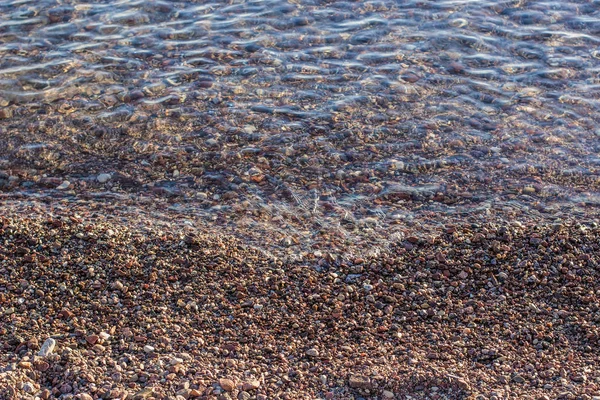 Verpletterd steen en ondiep water achtergrond strand landschap — Stockfoto