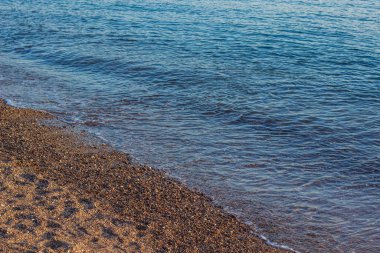 Ezilmiş taş ve okyanus insanlarının olmadığı boş bir sahil manzarası. Sakin su manzarası, uzay kopyası.